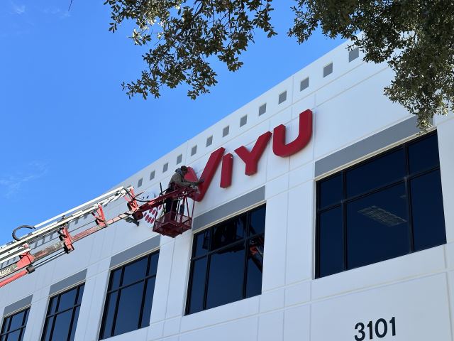 Commercial sign installers positioning illuminated building letters